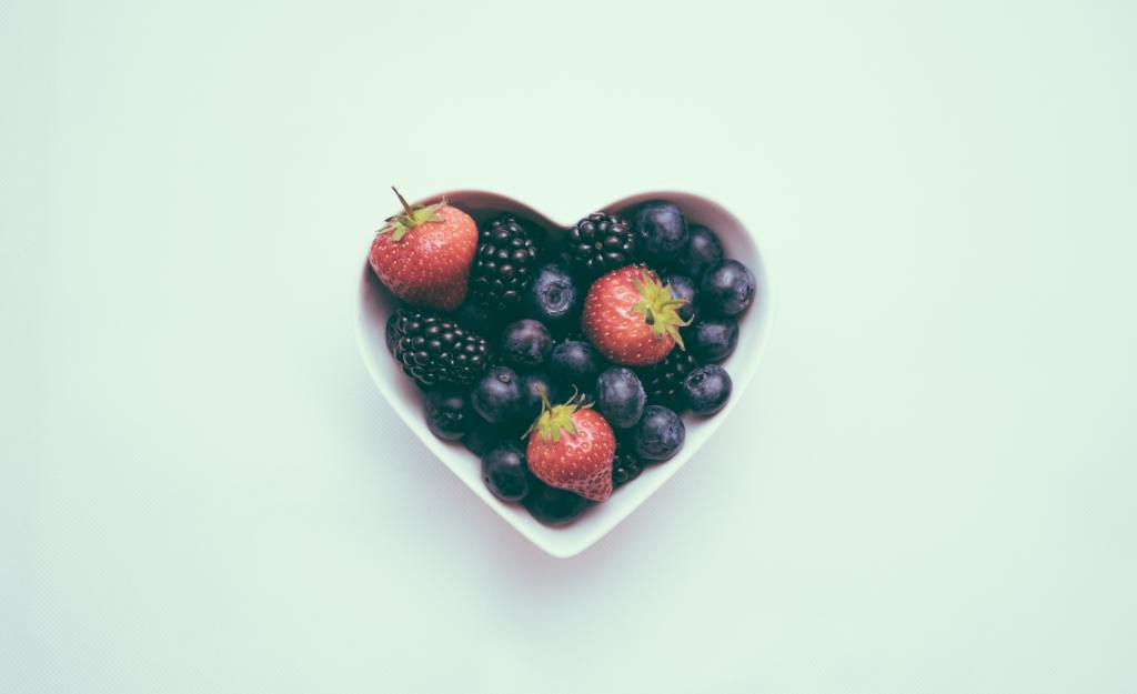 Heart shaped bowl filled with berries.