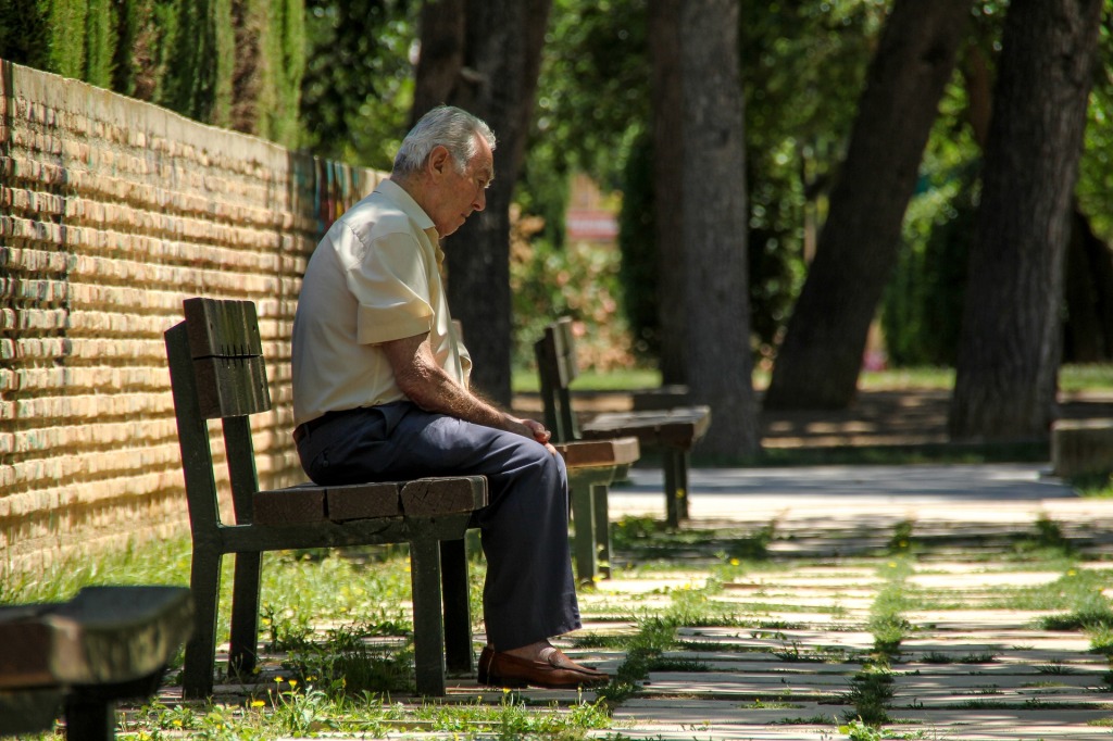 An elderly man sitting on a bench.